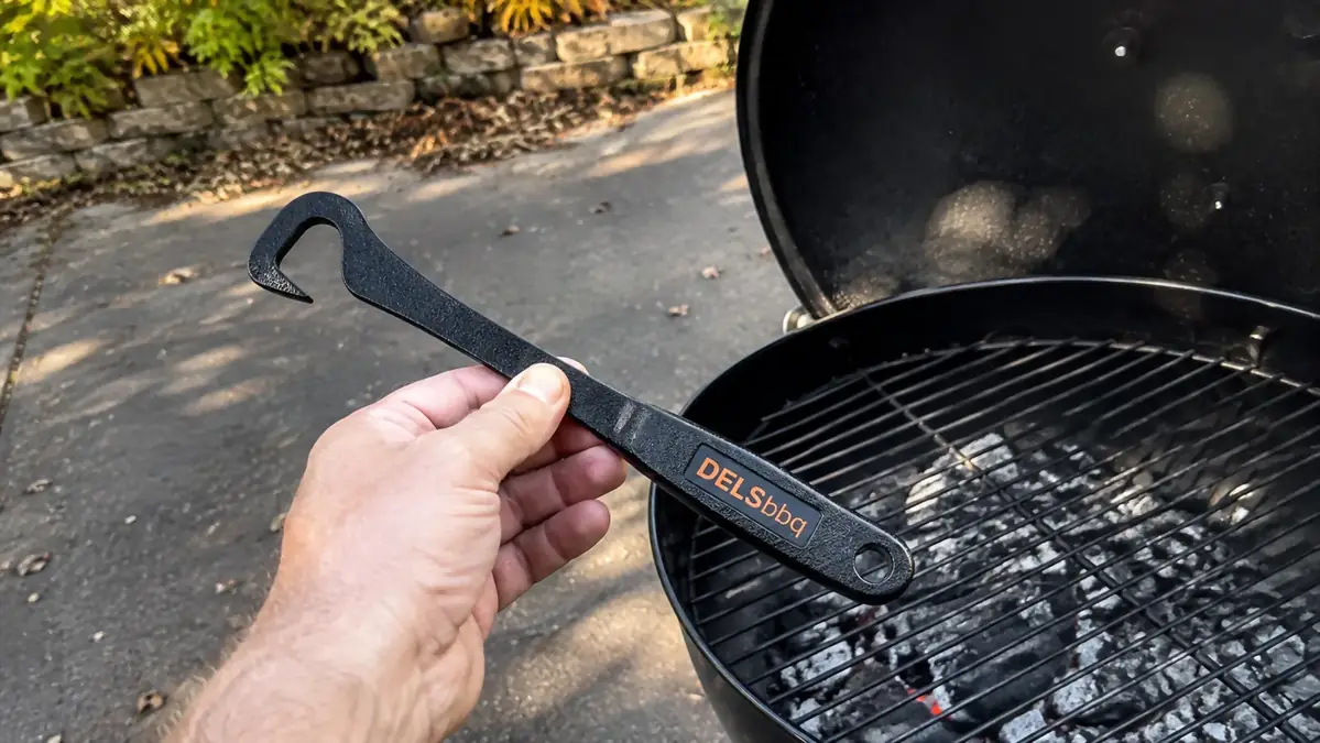 A hand using the DELSbbq cast iron grate lifter to check a grate for coating wear near the hook end