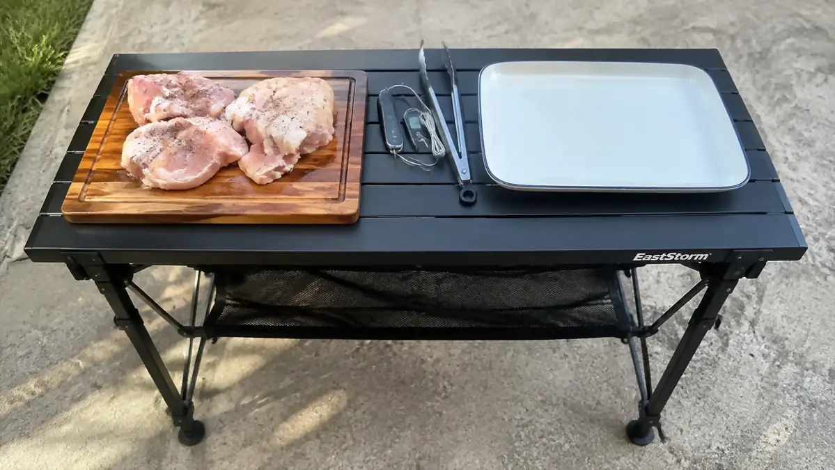 A folding table divided into a raw prep zone on one end and a landing zone for finished food on the other